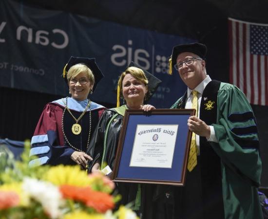 Professor of Occupational Therapy Mary Siniscaro stands between Provost Todd Pfannestiel and President Laura Casamento, 在2023年本科毕业典礼上颁奖.